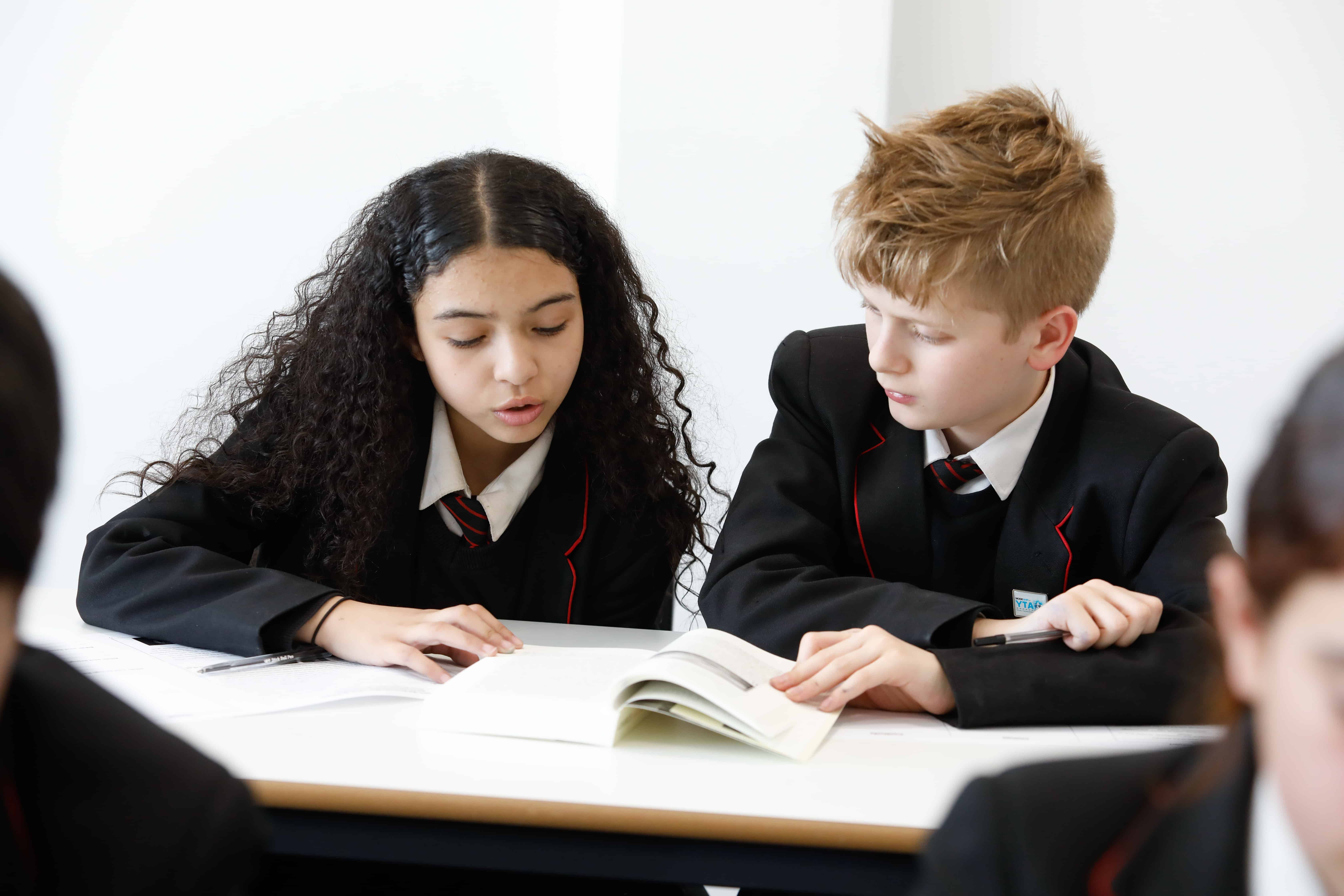 Image of two students at Didsbury High School reading from a textbook.